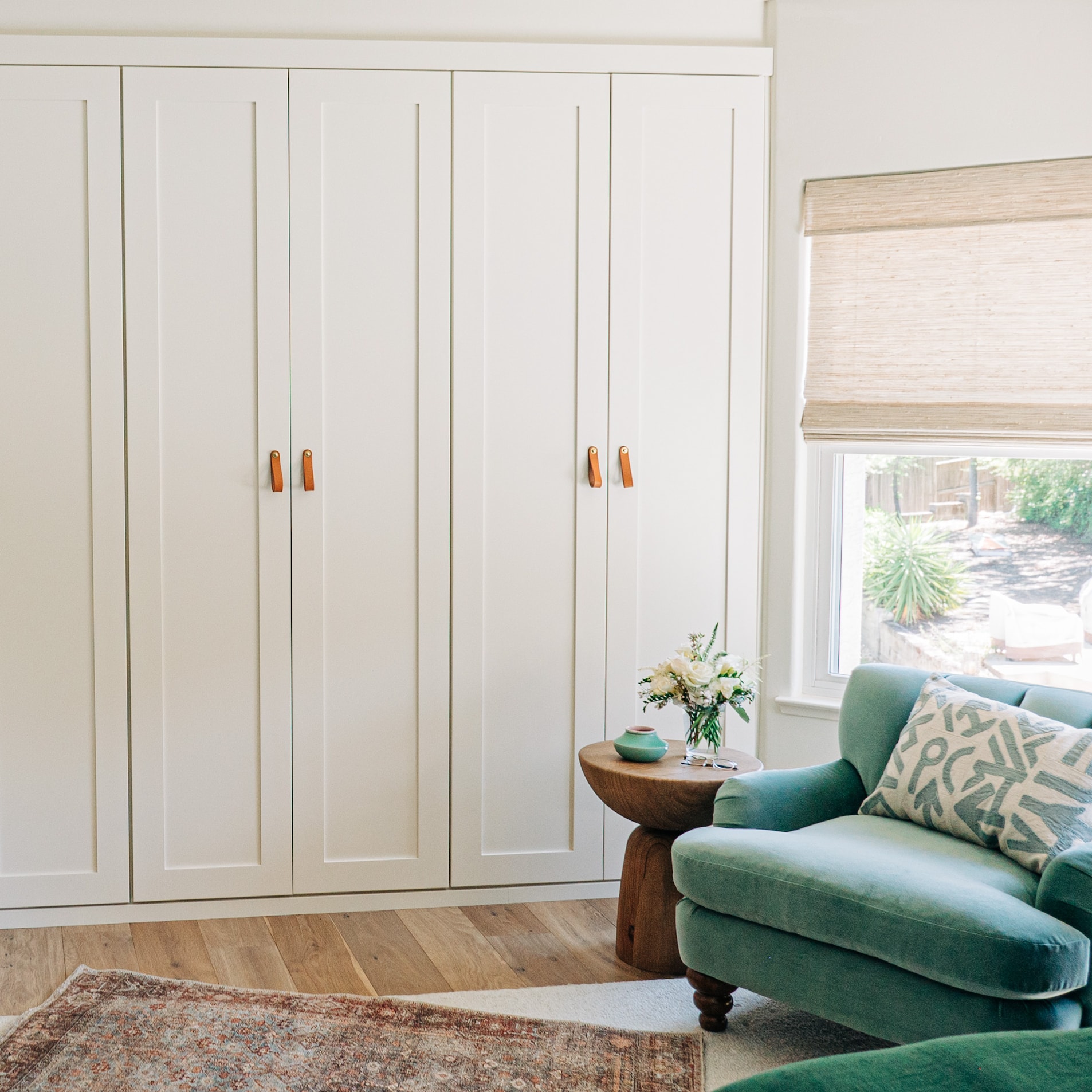 White built-in cabinetry and a green armchair in a sunlit room