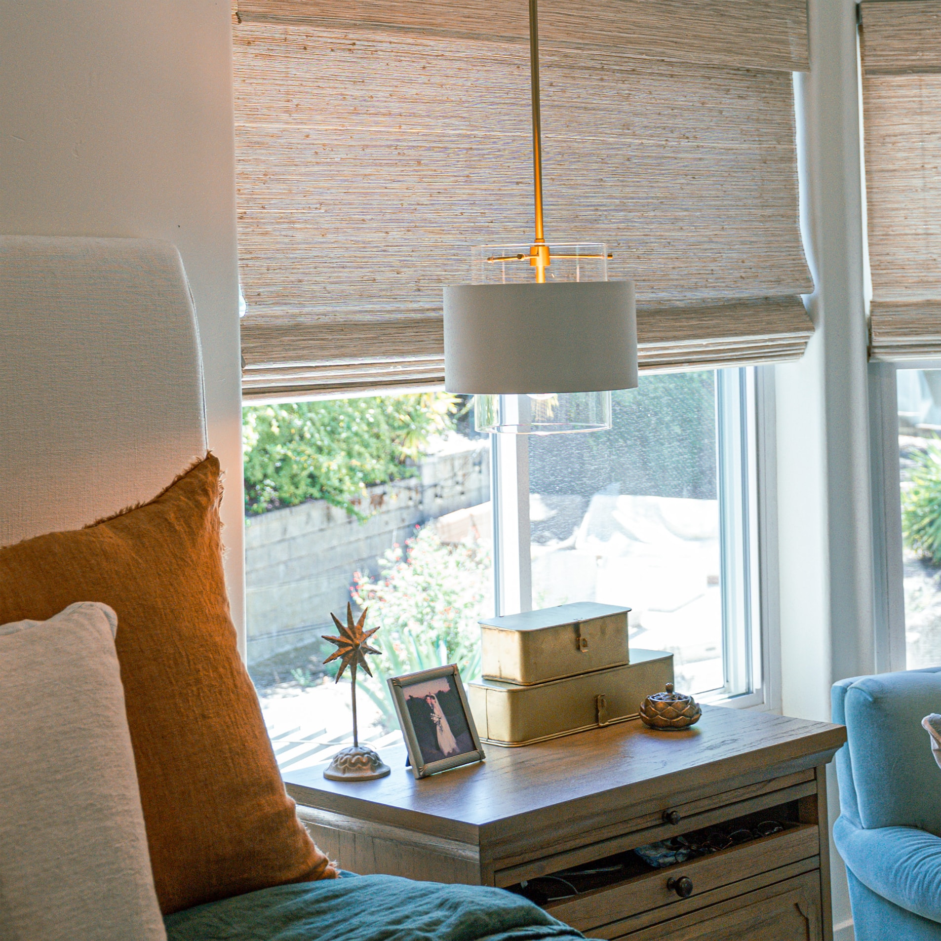 A pendant lamp over a window seat with layered cushions
