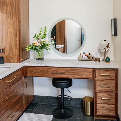 A wood vanity and a circular mirror